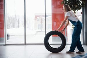 Mujer con una rueda de coche frente a una puerta de cristal